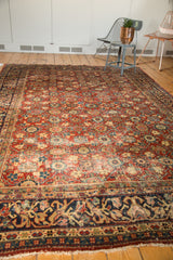 Vintage Mahal rug featuring intricate navy border with floral and vine motifs, cherry red field, and delicate fringe.