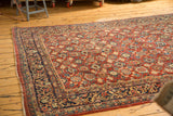 Vintage Mahal carpet's cherry red floral field, navy border, and tattered side edge.