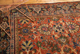 Rich terra cotta field of a vintage Mahalati carpet with oversized palmettes and navy blue border.