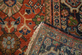 Vintage Mahalati rug: hand-knotted pile, terra cotta field, navy border, and ivory fringe.