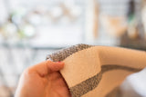 Handwoven cotton dish towel showcasing black and cream ticking stripe texture.