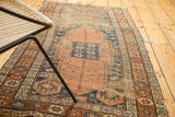 Antique Kurdish runner corner: worn terra cotta field, indigo geometric borders and starburst motifs.