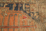 Detailed antique Kurdish rug showing worn terra cotta, indigo, sky blue pinwheel motifs, visible foundation.