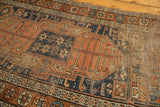 Heavy foundation showing through the worn pile of an antique Kurdish runner, terra cotta and indigo hues.