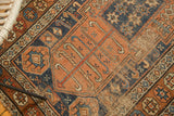 Detail of antique Kurdish runner, showing heavy foundation, terra cotta field, and indigo starburst motifs.