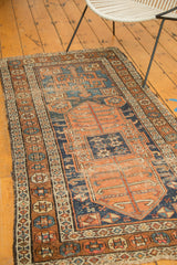 Antique Kurdish rug corner, displaying intricate geometric border and rich, time-softened hues.