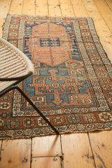 Geometric border in coffee brown, terra cotta, blue on an antique Kurdish rug, tattered ends.