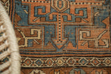 Antique Kurdish rug close-up: geometric pinwheel pattern in terracotta, sky blue, and brown.