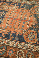 Antique Kurdish rug close-up: terra cotta field, indigo geometric patterns, even pile wear.