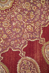 Vintage Amritsar rug close-up: wine red cartouche border, mauve floral field, visible wear.