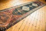 Abrashed dark field on a vintage Kurdish Bijar runner, framed by brick red and sky blue borders.