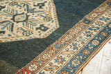 Detail of vintage Kurdish Bijar rug's abrashed charcoal field and patterned ivory border.