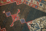 Geometric brick red and sky blue motifs on the abrashed charcoal field of a Bijar rug.