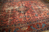 Abrashes visible on the antique Lilihan carpet's raspberry field with sapphire indigo motifs.