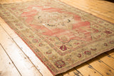 Antique Kerman rug's scalloped border with ivory, sage, and cochineal red floral palmettes.