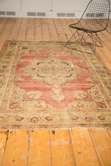 Antique Kerman rug border with floral motifs in ivory, green, and blush, showing worn edge.