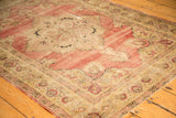Blush field and scalloped ivory border with floral palmettes on an antique Kerman rug.