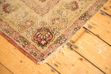 Antique Kerman rug corner detail, revealing tattered edge and blush cochineal red floral border.