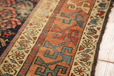 Intricate geometric border of an antique Kurdish Hamadan runner in rust, beige, and blue.