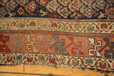 Antique Kurdish Hamadan rug detail: madder red geometric borders, indigo field, and tattered edge.
