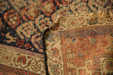 Detail of antique Kurdish Hamadan rug with indigo field, woven back, and tattered fringe.