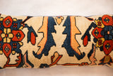 Hand-knotted rug fragment pillow with bold navy, burnt orange, and cream geometric pattern.
