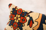Pillow corner showcases hand-knotted rug fragment with geometric red, navy, and yellow motifs.