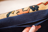 Hand revealing hidden black zipper on navy brushed cotton lumbar rug fragment pillow.