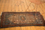 Vintage Malayer rug corner: man motif in sky blue spandrel, dusty rose field, tattered fringe.
