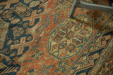 Antique Soumac carpet detail: intricate geometric patterns in pale brick red, indigo blue, faded saffron, showing even wear.