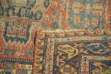 Folded corner revealing intricate geometric Soumac flatweave in brick red, indigo, and ivory.
