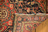 Vintage Persian Hamadan rug's folded edge, showing worn brick red floral border and navy field.