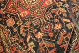 Vintage Persian Hamadan rug detail: allover floral cross sections, vinery in navy, brick red, with visible white knots.