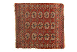 Antique Turkmen square rug with repeating triple gul motifs in wine red, terra cotta, navy, and ivory, showing tattered edges.