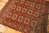Antique Turkmen rug's wine red gul motifs, navy, peach, ivory, with softened pile and frayed edges.