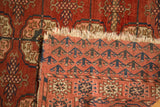 Antique Turkmen rug showing geometric pile, woven reverse pattern, and tattered fringe.