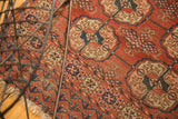 Antique Turkmen hand-knotted rug detail shows repeating red, navy gul motifs with tatter.