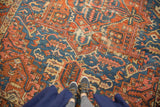 Feet on antique Karaja rug, showing rectilinear sky blue and brick red patterns with visible wear.