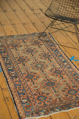 Tattered side edge of an antique Lilihan rug, featuring apricot and blue geometric patterns.