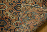 Antique Lilihan rug close-up: geometric pattern in apricot, blue, and brown, with a tattered folded edge.