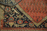Persian Malayer rug corner with navy spandrel, stylized motifs, and blush red abrash field.