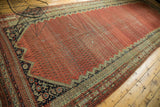Antique Malayer rug runner corner, showcasing serrated blush red field and intricate navy spandrel motifs.