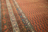Antique Malayer runner's detailed inner border with ivory and blue motifs, adjacent to the cinnabar red boteh field.