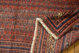 Antique Malayer rug corner showing intricate geometric borders, cream fringe, and brick red field.