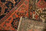 Visible foundation and detailed field of serrated leaves on a folded antique Malayer rug.