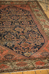 Antique Malayer rug section, displaying worn navy field, blush vinery, leaves, and animal figures.