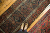 Antique Belouch runner displaying geometric patterns in time-softened navy, copper, and plum.