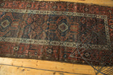 Antique Belouch runner's crisp geometric border and aged field in copper, navy, and ivory.