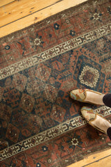 Antique Belouch runner detail: distinctive geometric border, trellis field in navy and dark copper tones.