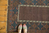 Fine antique Belouch rug detail: rich aubergine field, intricate geometric patterns, and ivory border.